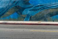 an elephant and baby whale painted on a wall near a street corner for a walk