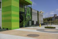 a large green building next to a parking lot in the daytime sun on a sunny day