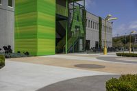 a large green building next to a parking lot in the daytime sun on a sunny day