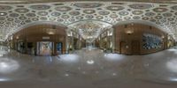 a fisheye view of a hallway with decorative ceilings and pictures hanging on the walls