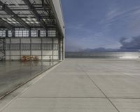 an airplane is parked inside of an enclosed building with windows overlooking water and mountains below