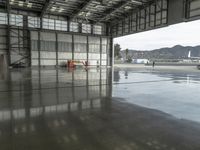 several workers work to clear out tarmac from the inside of the hangar area of a hangar