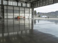 several workers work to clear out tarmac from the inside of the hangar area of a hangar