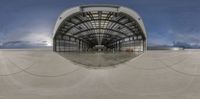 the view from inside a building through a fish eye lens, looking straight at a hangar