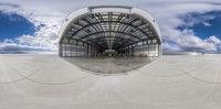 this is an image of a hangar under a cloudy sky with clouds, and one side in a circular mirror