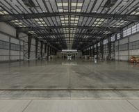 large, empty hangar with workers walking through it on a sunny day and waiting for something to happen