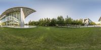 360 - pan shot of exterior of a modern building on green grass near trees and walkway