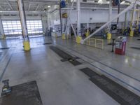 the empty factory floor with several equipment in it and a blue trash can behind it