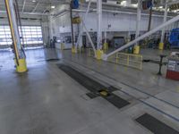 the empty factory floor with several equipment in it and a blue trash can behind it