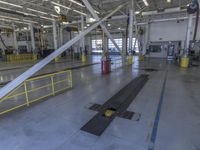 the empty factory floor with several equipment in it and a blue trash can behind it