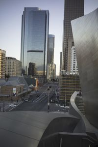 a city view with tall buildings and people on a street below and some cars on the road behind