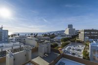 the sun is shining behind a high rise city view of an ocean beach, buildings and mountains