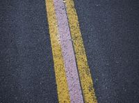 two yellow and pink lines painted on the asphalt in an area that seems to be a street