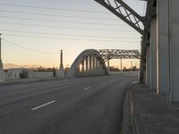 a long gray bridge and two people on it at sunset next to the freeway on which they are standing