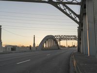 a long gray bridge and two people on it at sunset next to the freeway on which they are standing