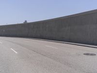 a freeway with a traffic sign on it next to an enormous concrete wall and gate