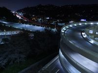 a long exposure shot shows an empty intersection at night with cars on the road and mountains