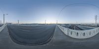 a wide angle fish eye view of traffic on the highway crossing over a fenced off bridge