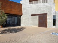 a brown building with brown walls and two metal doors on a sidewalk in front of it