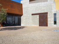 a brown building with brown walls and two metal doors on a sidewalk in front of it