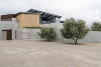 this house looks very neat and simple on a concrete surface with a stone wall and a garage that is behind it