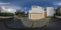 a view from a fish eye lens shows the exterior of a modern home with an unusual, curved driveway