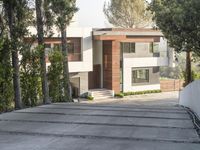 the exterior and landscape of a modern house in los angeles, california with stone and wood