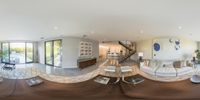 an oval living room, with a staircase going up to a second floor deck, with couches and tables around the space