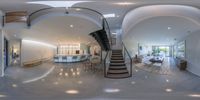 a spiral staircase leads to the first floor of a white - walled house with large open dining room and kitchen