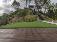 a patio with a wooden deck and artificial turf for putting a green putt on it