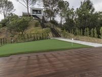 a patio with a wooden deck and artificial turf for putting a green putt on it