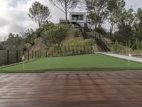 a patio with a wooden deck and artificial turf for putting a green putt on it