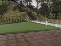 a patio with a wooden deck and artificial turf for putting a green putt on it