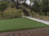 a patio with a wooden deck and artificial turf for putting a green putt on it