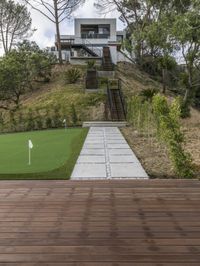 a patio with a wooden deck and artificial turf for putting a green putt on it