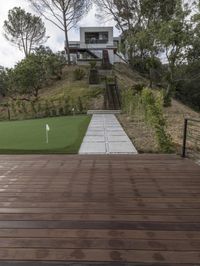 a patio with a wooden deck and artificial turf for putting a green putt on it