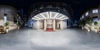 a hotel with circular columns and large windows in a dark night sky setting, illuminated by lights from an archway