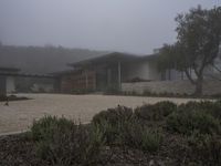 house with driveway, concrete and gravel driveway in foggy landscape area outside of residential residence