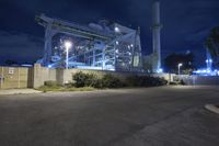 a view from the parking lot of an industrial building at night time with its lights on