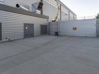 the front entrance of an industrial building with a work crane and large metal security gate