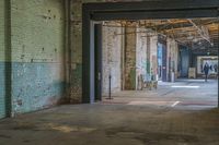 inside an industrial facility showing the street outside of it and people walking through the front