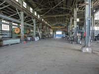 an empty industrial room with exposed ceiling and windows in the background is full of industrial equipment