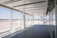 an empty room overlooking a tarmac, parked vehicles and glass walls with views of planes