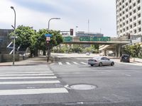 a busy intersection with a highway in the background and trees near by for pedestrians to turn