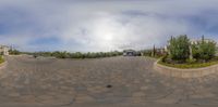 a 360 camera lens with a house in the distance and parked cars on both sides