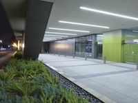 the interior of an empty building lit up at night time as people walk by it