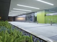 the interior of an empty building lit up at night time as people walk by it