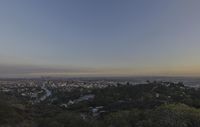 the town is in the distance with no clouds above it as the sun rises on the hill