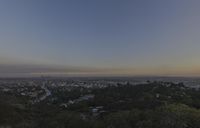 the town is in the distance with no clouds above it as the sun rises on the hill