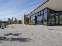 the large building has glass doors and windows in it's windows is next to a park